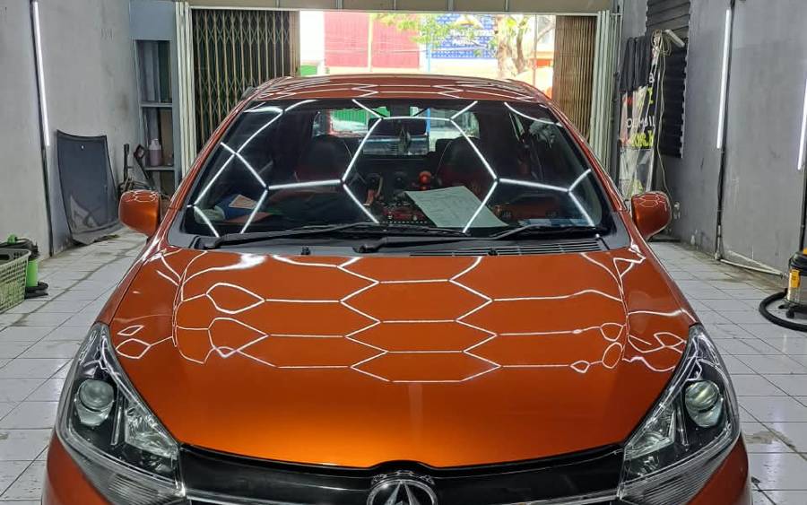 Hasil coating Otopia Gresik: cat oranye mengkilap memantulkan lampu bengkel